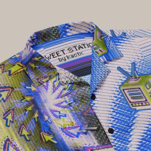 May include: A button-down shirt with a vibrant, abstract design. The shirt features a mix of blue, green, and white patterns, including arrows and a retro television graphic. The text "SWEET STATIC by kacix" is visible on the collar.