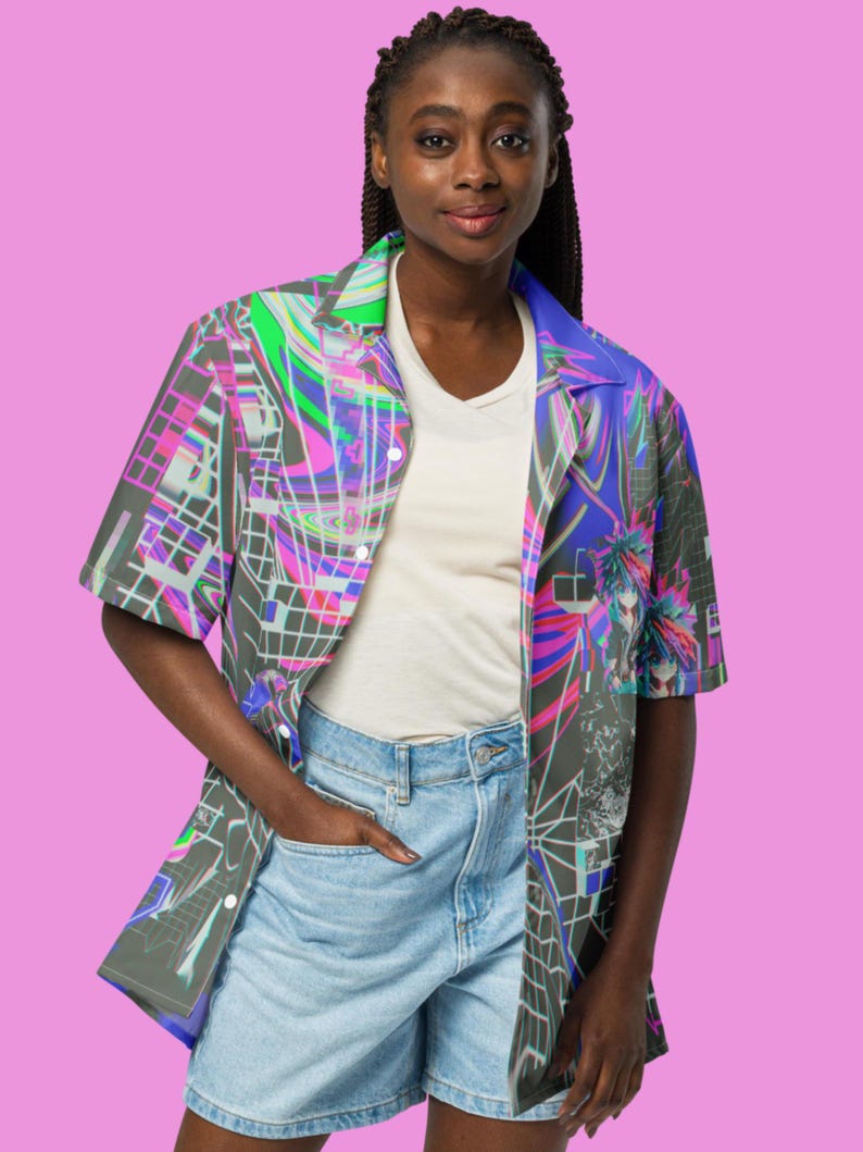 May include: A person wearing a short-sleeved button-up shirt with a colorful abstract print. The shirt has a blue, green, pink, and black design. The person is also wearing denim shorts.