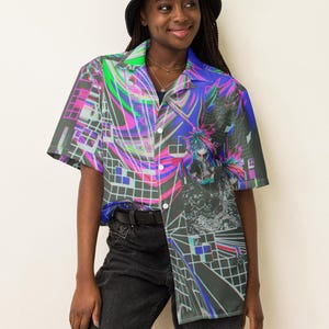 May include: A person wearing a black bucket hat and a short-sleeved button-up shirt with a colorful abstract print. The shirt has a black and white grid pattern with pink, blue, and green accents.