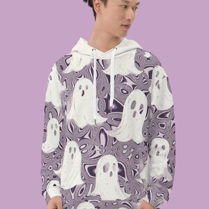 Puede incluir: Una sudadera con capucha blanca con un patr&oacute;n de remolinos p&uacute;rpura y blanco y siluetas de fantasmas blancas.