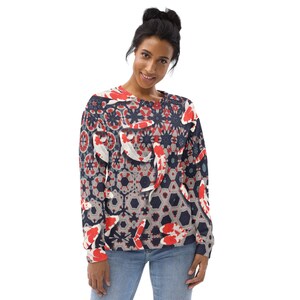 May include: A crew neck sweatshirt featuring a repeating pattern of koi fish in red, white, and gray against a navy blue background. The design incorporates geometric shapes and floral elements. The sweatshirt is worn by a person in blue jeans.