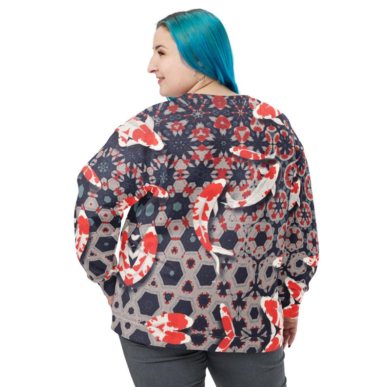 May include: A long-sleeved sweatshirt featuring a repeating pattern of red and white koi fish on a navy blue and gray geometric background. The design includes hexagonal shapes and floral elements, creating a unique and artistic look.