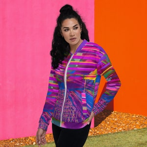 Puede incluir: Una mujer lleva una chaqueta bomber de color morado, azul y rosa con un patr&oacute;n geom&eacute;trico. La chaqueta tiene una cremallera y un cuello alto.