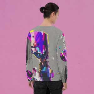 K&ouml;nnte beinhalten: Ein graues Sweatshirt mit einem bunten Grafikdruck einer Frau, die einen futuristischen Helm tr&auml;gt. Der Druck zeigt ein pixeliertes Design in den Farben Pink, Blau, Lila und Gelb.