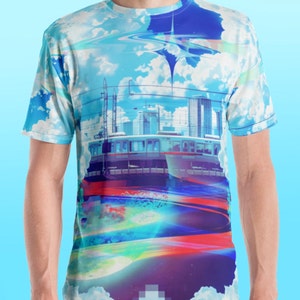 Op de afbeelding: Een blauw, wit en paars T-shirt met een grafische print van een skyline van een stad, een trein en een draaiende galaxie. Het ontwerp is abstract en heeft een gepixelde blauwe vierkant.