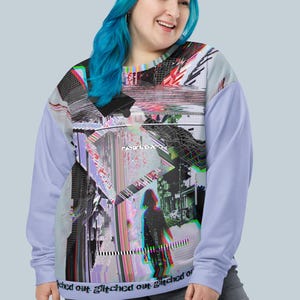 Peut inclure: Un sweat-shirt lavande avec un imprimé graphique défectueux représentant une ville et une personne marchant dans la rue. Le texte "glitch out" est répété sur l'ourlet inférieur du sweat-shirt.