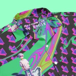 May include: A black and green button-up shirt with a psychedelic swirl pattern and a pixelated character. The shirt has a collar and a button closure. The text "Arrowmind by KACIX" is printed on the collar.
