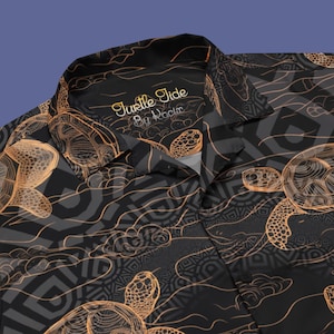May include: Black button-up shirt with a pattern of gold sea turtles and waves. The shirt has a label that reads "Juelle Tide by Nociir".