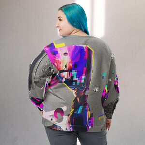 K&ouml;nnte beinhalten: Ein grauer Pullover mit einem bunten Grafikdruck, der eine Frau mit einer Virtual-Reality-Brille zeigt. Der Druck enth&auml;lt geometrische Formen, pixelartige Muster und eine futuristische Stadtlandschaft. Der Text "UNDERGROUND BY KYO" ist auf dem &Auml;rmel sichtbar.