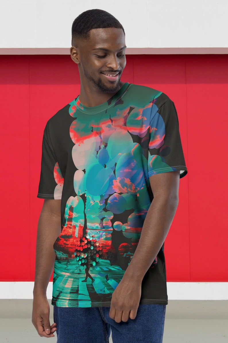 May include: A black t-shirt with a colorful abstract design featuring a cityscape with a person walking across a crosswalk. The design includes circles, clouds, and a sunset.