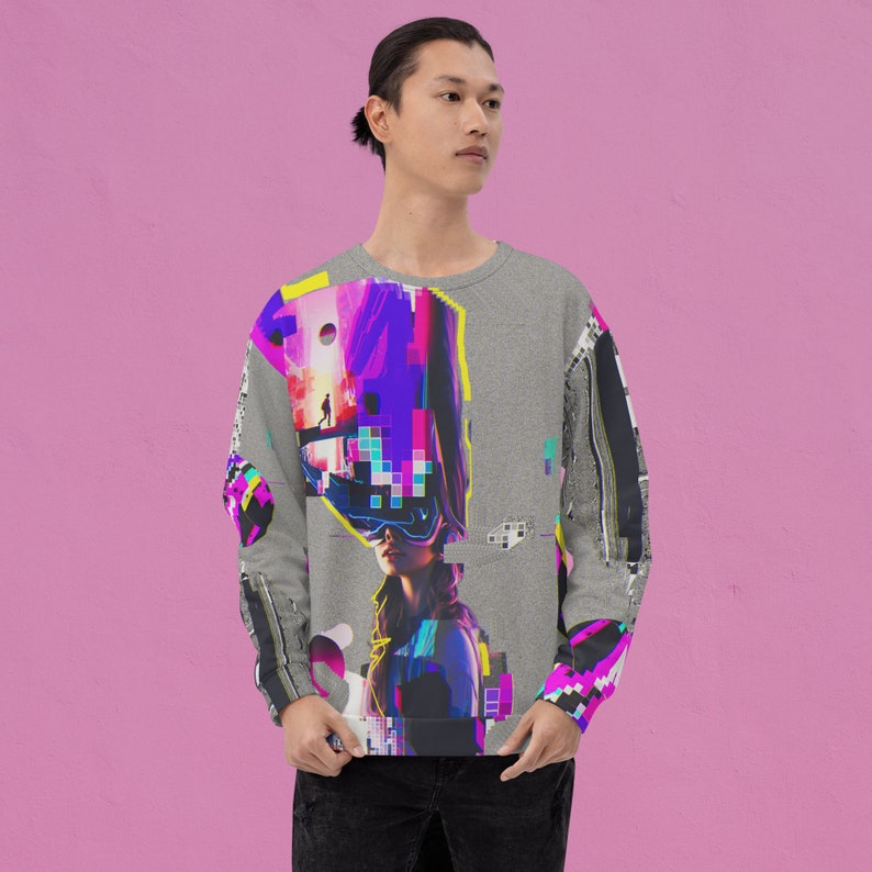 K&ouml;nnte beinhalten: Ein grauer Pullover mit einem farbenfrohen, abstrakten Design, das ein Frauen Gesicht, geometrische Formen und pixelige Elemente zeigt.