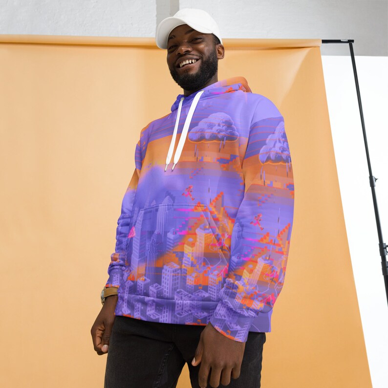 May include: A purple hoodie with an all-over cityscape design featuring buildings, clouds, and a sunset gradient. The hoodie has a white drawstring and a front pocket. The design incorporates shades of purple, orange, and pink.
