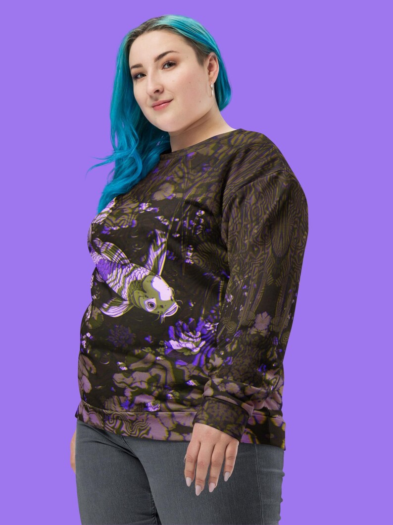 Puede incluir: Una sudadera negra con un estampado floral morado y verde que presenta un gran pez koi. La sudadera tiene mangas largas y cuello redondo.