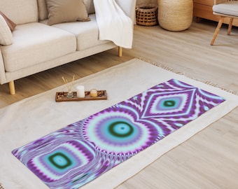 Puede incluir: Una esterilla de yoga con un diseño abstracto vibrante en tonos morado, turquesa y azul claro. El patrón presenta círculos concéntricos y formas de diamante, creando un efecto psicodélico. La esterilla es rectangular y está sobre una alfombra.