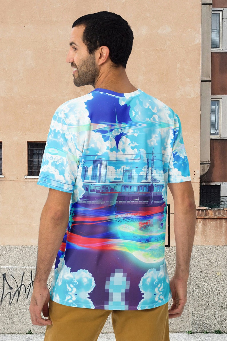 Op de afbeelding: Een blauw, wit en paars T-shirt met een grafische print van een stadsbeeld, wolken en een trein. De grafiek is een mix van gepixelde en realistische elementen.