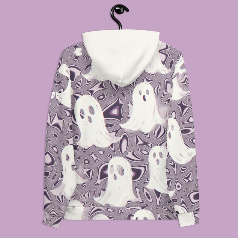 Puede incluir: Una sudadera con capucha de color morado y blanco con un patr&oacute;n de remolino y siluetas de fantasmas blancos. La sudadera tiene una capucha blanca.