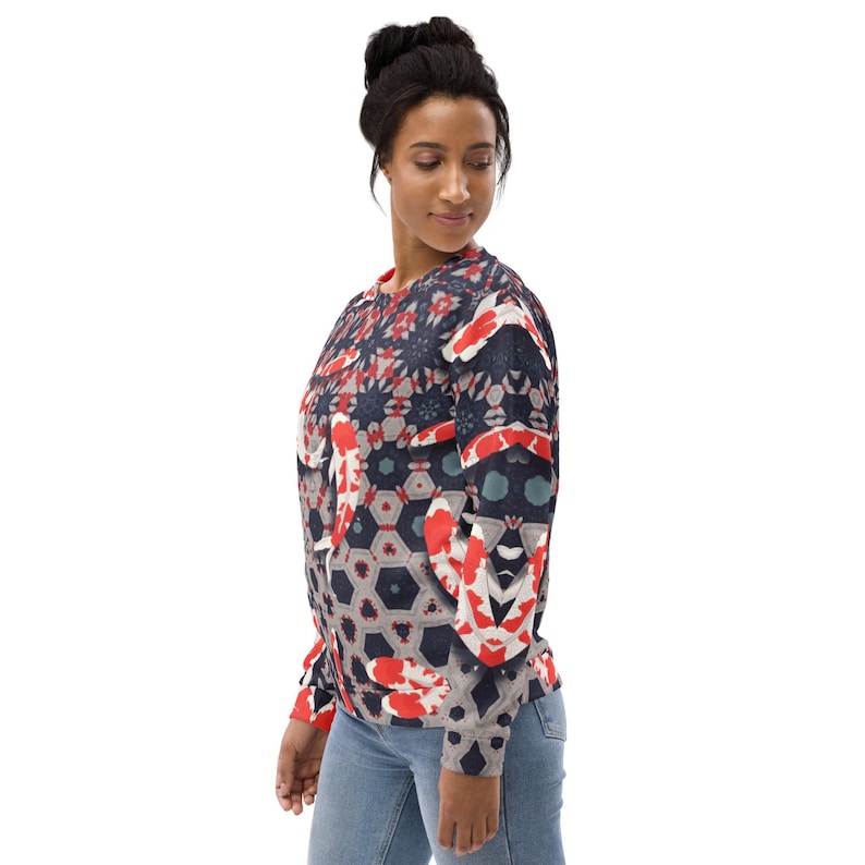 May include: A navy blue sweatshirt featuring a koi fish pattern in red, white, and gray. The design incorporates geometric shapes and floral elements. The long-sleeved top has a crew neck and a relaxed fit.