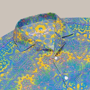 May include: A yellow, blue, and green patterned button-up shirt with a collar. The shirt has a label that reads "Sherbet Tapestry by Jenica".