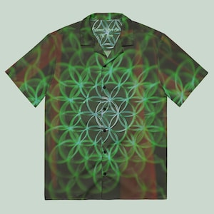 May include: Short-sleeved button-down shirt with a green and white geometric pattern. The shirt features a collar and a series of black buttons down the front. The inner collar has the text "Sacred Vibes Only By Rex". The shirt has a dark green and brown background.