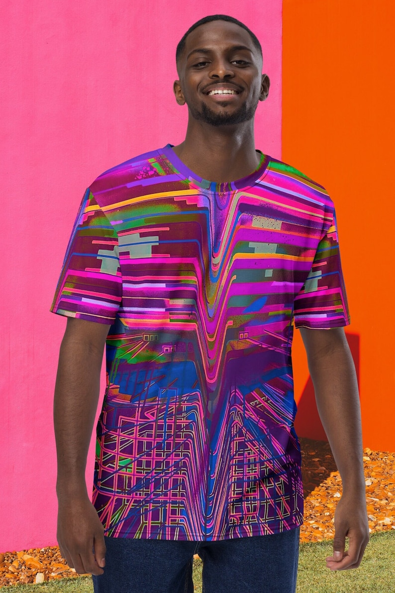 May include: A person wearing a short-sleeved t-shirt with a colorful abstract design. The design features a mix of pink, purple, blue, green, and yellow lines and shapes.
