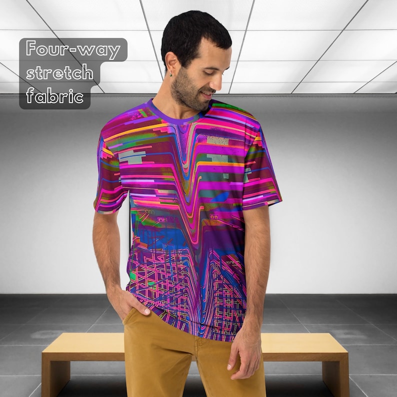 May include: A person wearing a short-sleeved t-shirt with a colorful abstract design. The shirt has a purple, pink, blue, and yellow color scheme. The text "Four-way stretch fabric" is visible in the top left corner of the image.