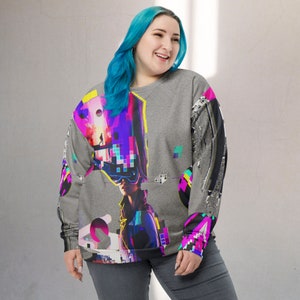 K&ouml;nnte beinhalten: Ein graues Sweatshirt mit einem bunten Grafikdruck einer Person, die ein Virtual-Reality-Headset tr&auml;gt. Die Grafik hat ein pixeliges Design in den Farben Pink, Blau, Lila und Gr&uuml;n.