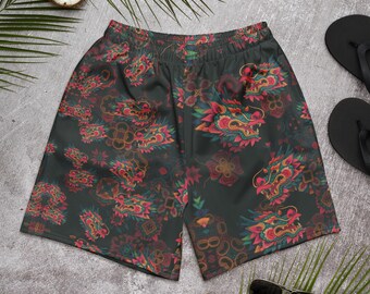 Puede incluir: Pantalones cortos deportivos de color gris oscuro con un patrón repetido de cabezas de dragón coloridas y diseños florales. Los dragones presentan acentos rojos, rosas y dorados. Los pantalones cortos tienen una cintura elástica.