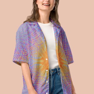 May include: A button-down shirt with a vibrant, abstract design in shades of purple, orange, and blue. The shirt is worn over a white t-shirt and paired with blue jeans. The overall style is casual and colorful.