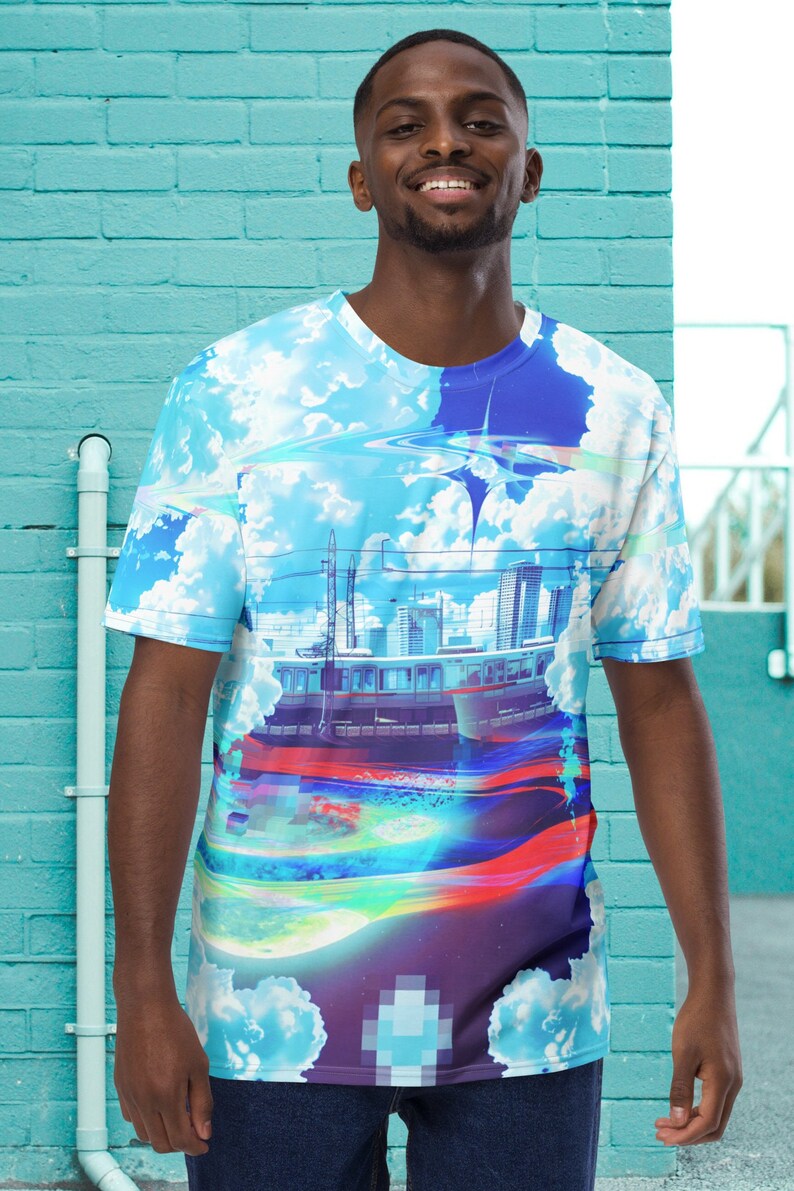 Op de afbeelding: Een blauw, wit en rood t-shirt met een grafische print van een skyline en wolken. De grafiek heeft een gepixeld effect en een regenboogkleurige streep.