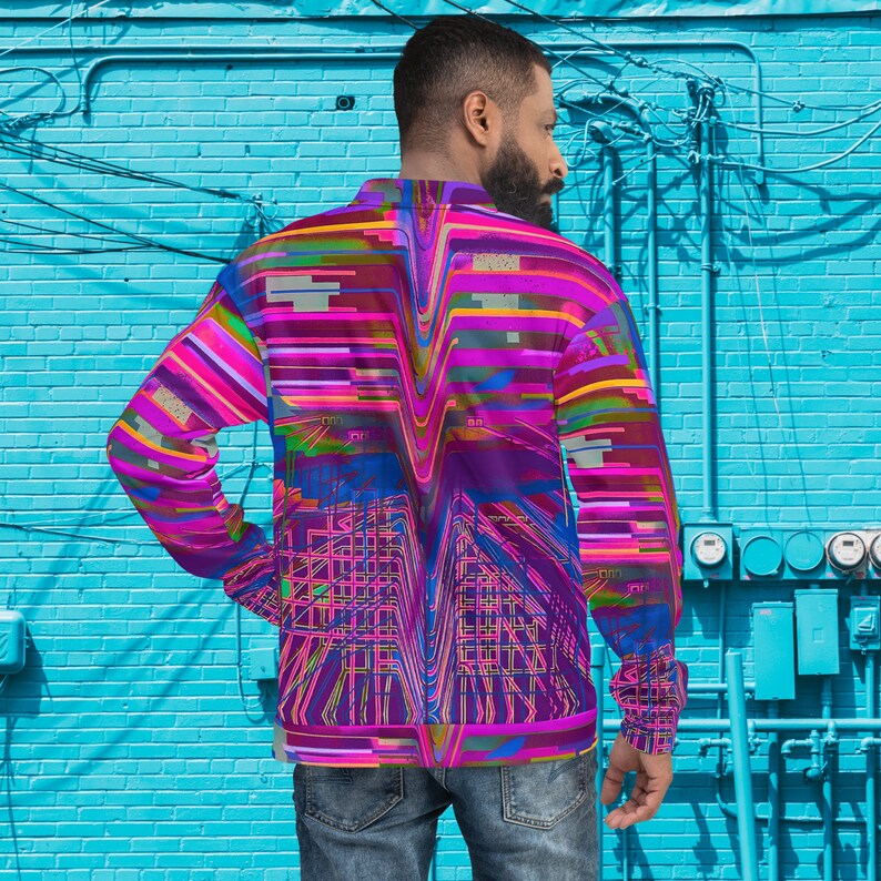 Puede incluir: Una camisa de manga larga con un estampado abstracto colorido que presenta formas geom&eacute;tricas y l&iacute;neas en tonos de rosa, azul, verde y amarillo. La camisa tiene una cremallera y un corte holgado.