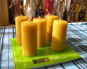 May include: Five yellow beeswax candles on a green digital scale with the brand name "ORION" printed on the scale. The candles are arranged in a row on the scale.