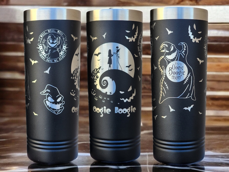 May include: Three black stainless steel tumblers with different Nightmare Before Christmas designs. The first tumbler features the text "Well, well, well, what have we here?" and a character with a stitched face. The second tumbler features the text "Oogie Boogie" and a character with a stitched face. The third tumbler features a scene from the movie with Jack Skellington and Sally.