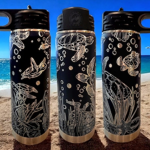 May include: Three black stainless steel water bottles with a silver lid and handle. Each bottle features a white outline design of sea turtles and bubbles on a black background.