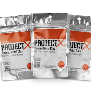 May include: Three silver-coloured foil pouches of Five Star PROJECT X Copper Metal Clay. Each label features the text 'Kiln Fire', '11-15% Shrinkage', a QR code for instructions, and the website ClayRevolution.com. The pouches are labelled 25g, 50g, and 100g.