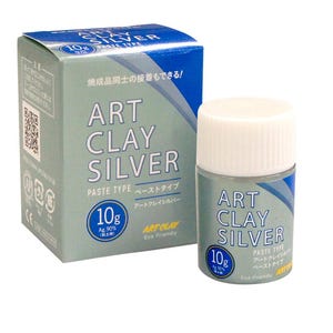 May include: A 10g container of Art Clay Silver paste type and its matching cardboard box. The packaging is light blue and white with the text Art Clay Silver, 10g, and Ag 90% printed on the front. The container has a white screw-on cap.