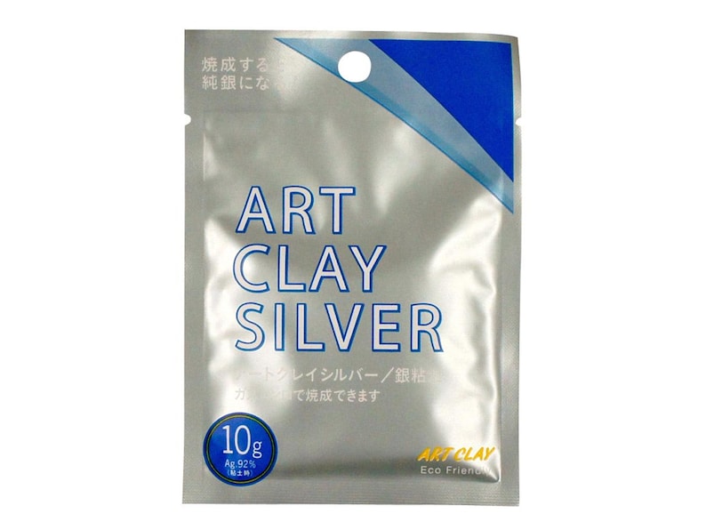 May include: A silver-colored rectangular foil pouch labeled ART CLAY SILVER in blue text. The packaging features a blue diagonal stripe at the top, a circular 10g weight indicator, and Japanese text. The bottom right corner displays the text ART CLAY Eco Friendly.