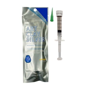 May include: A 10g package of Art Clay Silver in a silver metallic pouch with blue accents, featuring the text Art Clay Silver. Beside it is a clear plastic syringe filled with silver clay, a white plunger, and a separate small green nozzle tip.