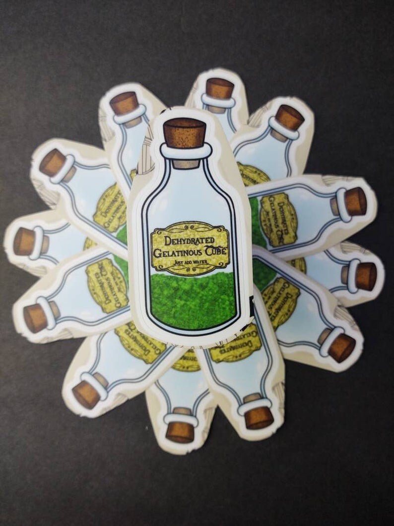 May include: A sticker of a glass bottle with a cork stopper. The bottle is filled with a green substance and has a yellow label that reads "Dehydrated Gelatinous Cube. Just add water."
