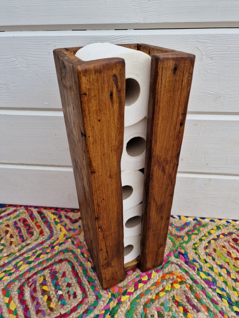 May include: A rustic wooden toilet paper holder with a dark brown stain. The holder is designed to hold four rolls of toilet paper.