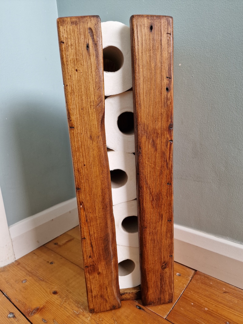 May include: A rustic wooden toilet paper holder with a dark brown stain. The holder has four slots for toilet paper rolls.