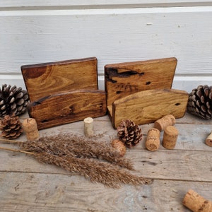May include: Two rustic wooden holders with a rounded top, perfect for displaying items like business cards or recipe cards. The holders are made of reclaimed wood and have a natural, distressed finish.