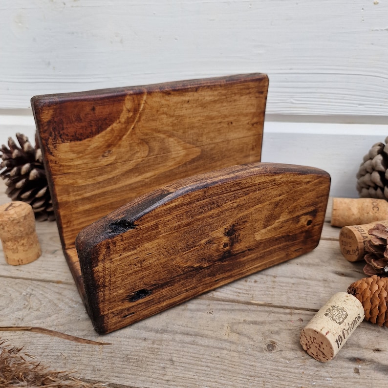 May include: A rustic wooden wine bottle holder with a dark brown stain. The holder has a curved top and a rectangular base.