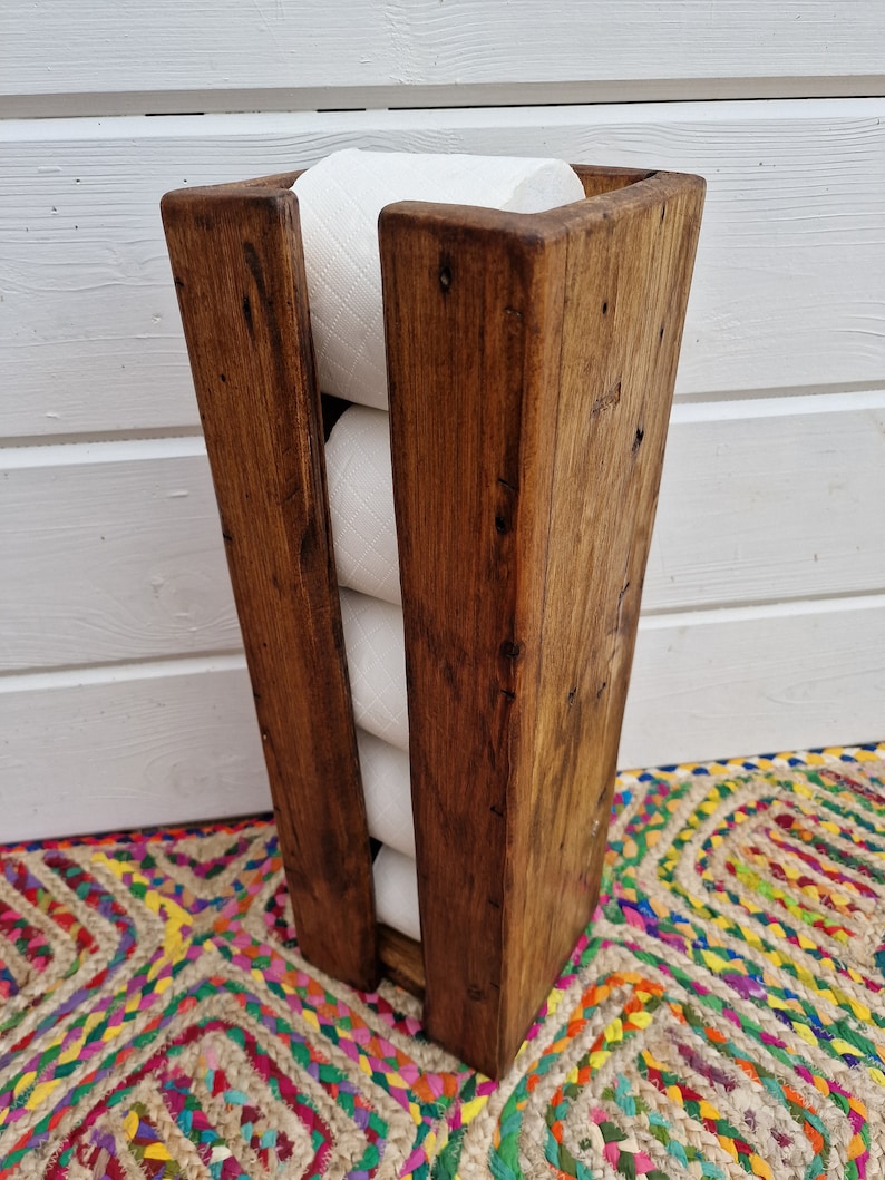 May include: A rustic wooden toilet paper holder with a dark brown stain. The holder is designed to hold four rolls of toilet paper.