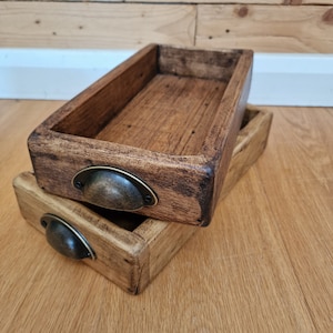 May include: Two wooden trays with dark brown stain and metal handles. The trays are stacked on top of each other.