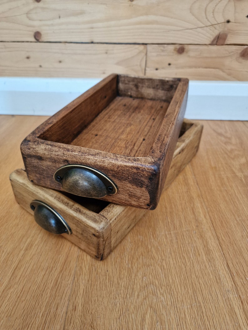 May include: Two wooden trays with dark brown stain and metal handles. The trays are stacked on top of each other.