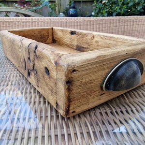 May include: A rustic wooden tray with a dark brown metal handle. The tray is made of reclaimed wood and has a natural finish.