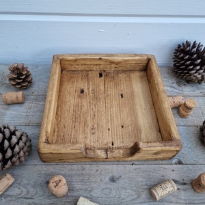 K&ouml;nnte beinhalten: Ein rustikales Holztablett mit rechteckiger Form und leicht erh&ouml;htem Rand. Das Tablett ist aus Naturholz in hellbrauner Farbe mit einer abgenutzten Oberfl&auml;che. Das Tablett hat einen kleinen Ausschnitt vorne f&uuml;r einfachen Zugriff.