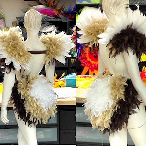 May include: A costume set featuring a feathered shoulder piece and a matching feathered back attachment. The design incorporates layered white, tan, and dark brown feathers arranged in a dense, textured pattern across the shoulders and lower back.