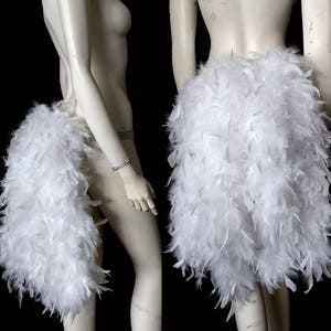 May include: Two white feather boas, one worn as a skirt and the other as a tail. The boas are made of soft, fluffy feathers and are perfect for adding a touch of glamour to any outfit.