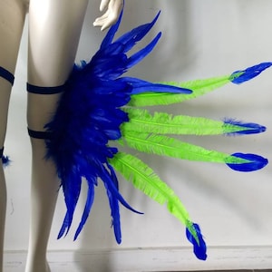May include: Blue and green feather leg piece with black elastic straps. The feathers are arranged in a fan shape with the blue feathers on the inside and the green feathers on the outside.